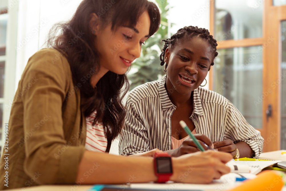 Obraz premium Delighted young female making notes during lesson