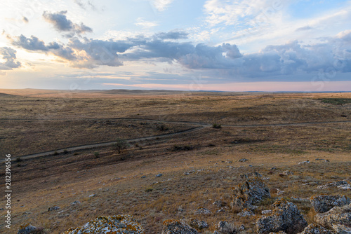 Dawn on a mountain in the steppe of the Opuksky nature reserve with yellow grass, with clouds on the sky, shot during the season of golden autumn. Yellow-golden brown.