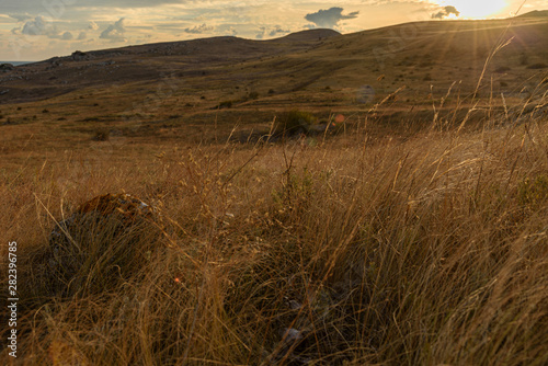 Dawn on a mountain in the steppe of the Opuksky nature reserve with yellow grass  with clouds on the sky  shot during the season of golden autumn. Yellow-golden brown.