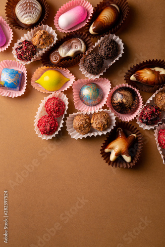 Chocolate bonbons set on brown background top view