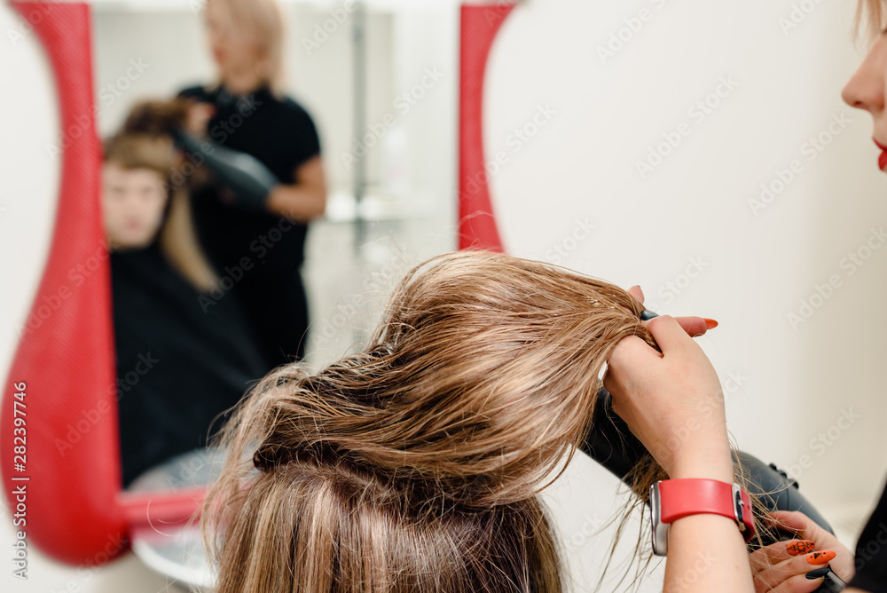 Fototapeta premium Closeup of professional stylist drying hair of female client