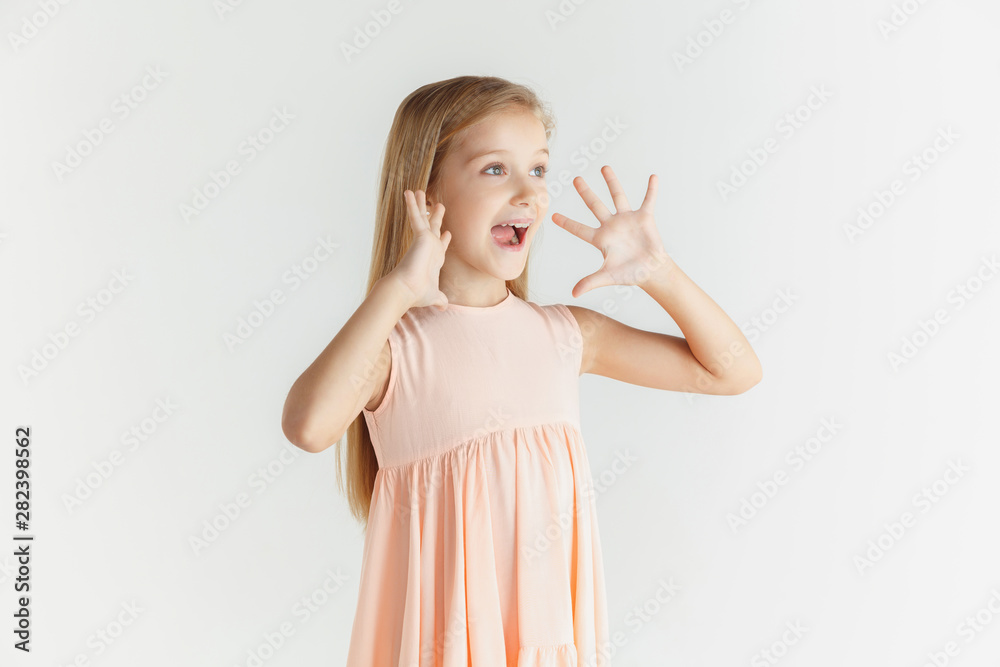 Stylish little smiling girl posing in dress isolated on white studio background. Caucasian blonde female model. Human emotions, facial expression, childhood. Calling, astonished, wondered. Stylish little smiling girl posing in dress isolated on white studio background. Caucasian blonde female model. Human emotions, facial expression, childhood. Calling, astonished, wondered.