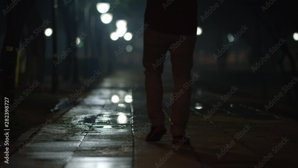 Back view of a man walking at city street in Saudi Arabia after rain at night. Back view of a man walking at city street in Saudi Arabia after rain at night.