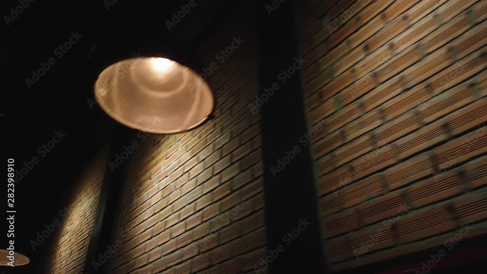 A Film Noir suspense mystery drama waiting to unfold late at night in a dark alley with pools of old fashioned industrial down lighting on a brick wall in old Saigon but the location could be anywhere