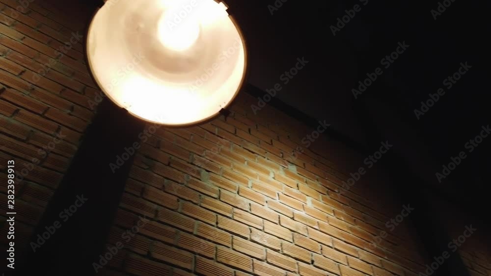 A Film Noir suspense mystery drama waiting to unfold late at night in a dark alley with pools of old fashioned industrial down lighting on a brick wall in old Saigon but the location could be anywhere