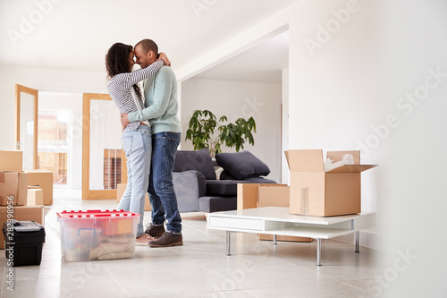 Loving Couple Hugging Surrounded By Boxes In New Home On Moving Day © Monkey Business