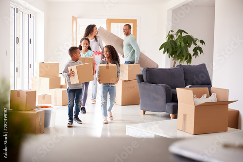 Smiling Family Carrying Boxes Into New Home On Moving Day photo