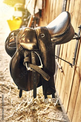 leather horse saddle in a stable hanging on the wall.