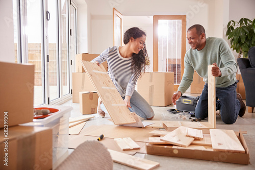 Couple In New Home On Moving Day Putting Together Self Assembly Furniture photo