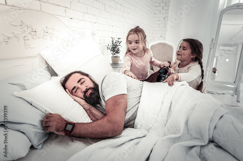 Cute girls waking up their father in the morning