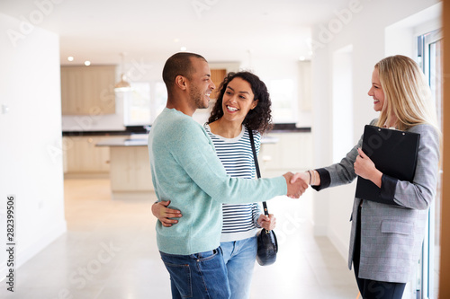 Female Realtor Shaking Hands With Couple Interested In Buying House photo