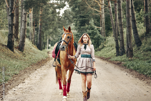 beautiful girl goes on the road with a horse.