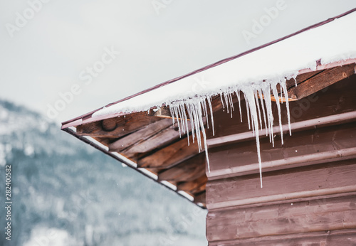 Icicles hanging from roof of mountain hut against winter snowy landscape