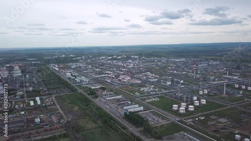 View from above of large industrial area located outside the city with fields and trees on the background against cloudy sky. Clip. Amazing view of factories tanks and tank farm. photo