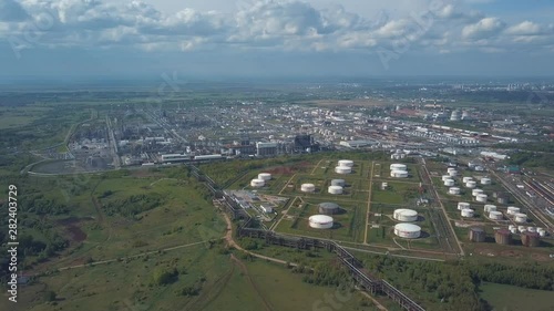 Aerial view of field with trees near the industrial area located outside the city. Clip. Amazing view of factories tanks and tank farm for bulk petroleum and gasoline storage photo