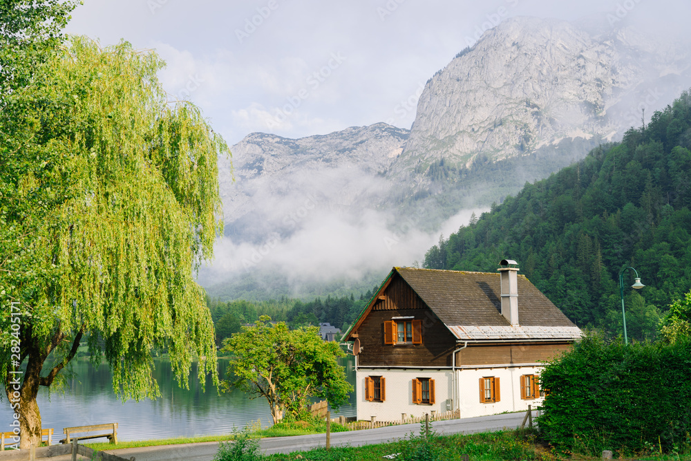 Morning in the Alps. Beautiful foggy morning scenery in Alps region, Austria. Great morning view of foggy mountains, fog, house and green meadow in Austria
