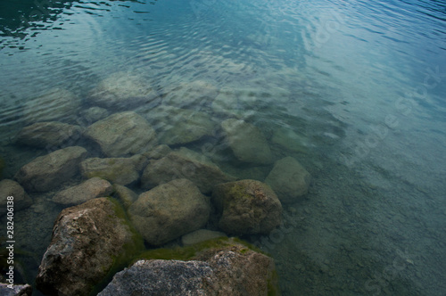 Fototapeta Naklejka Na Ścianę i Meble -  Rough stones are visible through the clear water of the lake.
