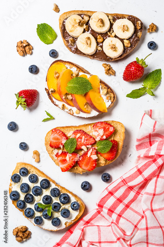 Sweet toast assortment with fresh fruit and berries on white.