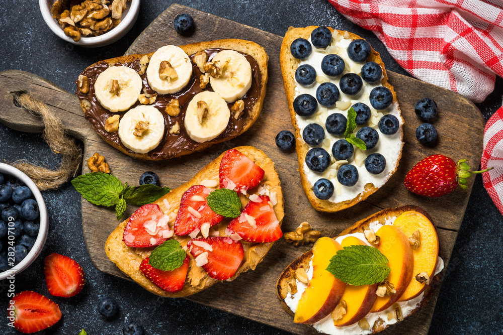 Sweet toast assortment with fresh fruit and berries on black. Sweet toast assortment with fresh fruit and berries on black.