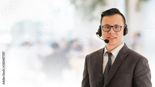 Portrait of Asian smiling businessman customer support phone operator in office space background and copy space.Concept call center job and telemarketing service.