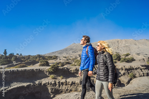Young couple man and woman visit the Bromo volcano at the Tengger Semeru National Park on the Java Island, Indonesia. They enjoy magnificent view on the Bromo or Gunung Bromo on Indonesian, Semeru and