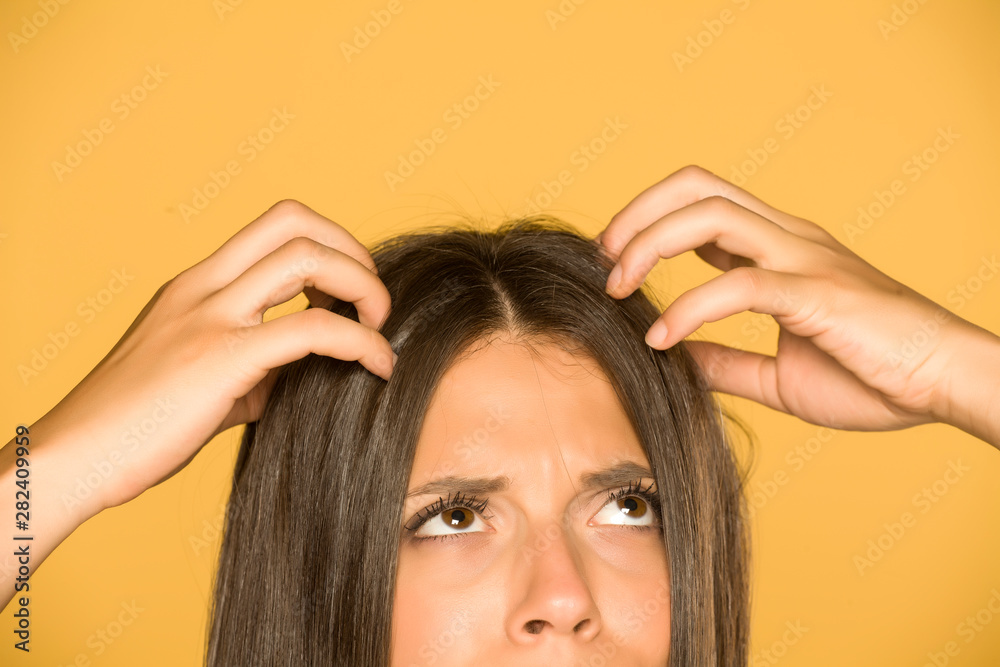 Beautiful young woman with itchy scalp on yellow background - obrazy, fototapety, plakaty 