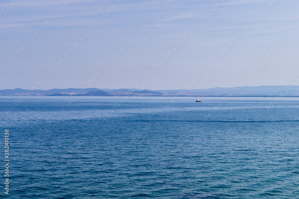 Panorama of the Tuscan sea with a sailboat.