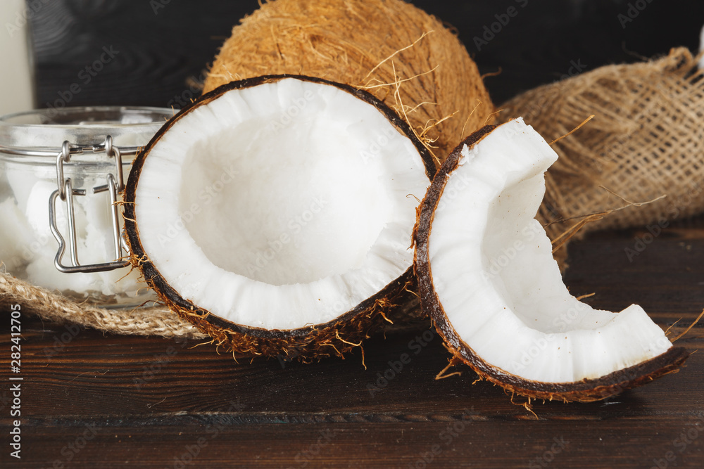 Broken coconut on a dark aged wooden table close up Broken coconut on a dark aged wooden table close up