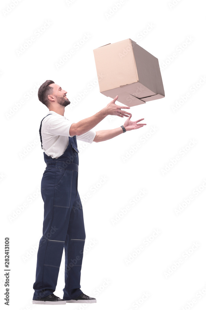 side view. smiling man in overalls catches a cardboard box side view. smiling man in overalls catches a cardboard box