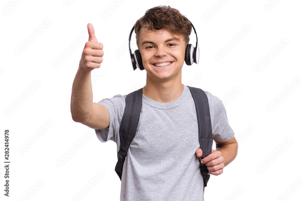 Happy teen boy with headphones and backpack, isolated on white background. Cheerful child listening to music and making Thumb up Gesture. Emotional portrait of handsome teenager guy Back to school. Happy teen boy with headphones and backpack, isolated on white background. Cheerful child listening to music and making Thumb up Gesture. Emotional portrait of handsome teenager guy Back to school.