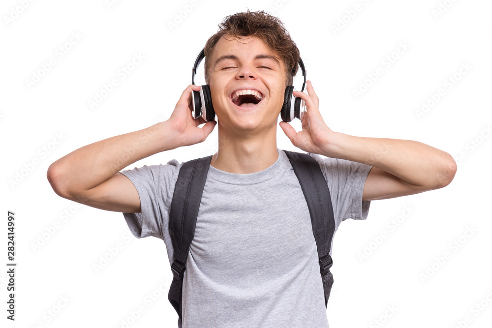 Happy teen boy with headphones and backpack, isolated on white background.  Cheerful child listening to music and singing song. Emotional portrait of  handsome teenager enjoying music Back to school. Stock Photo |