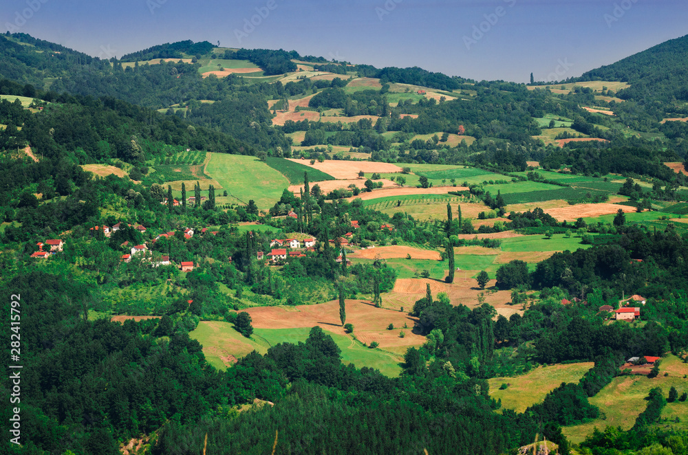Landscape view of mountain farmland with village houses and tall cypress trees