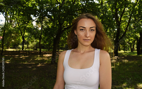 Young serious girl in white t-shirt in dark forest.