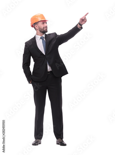 in full growth. young businessman in helmet pointing to copy space