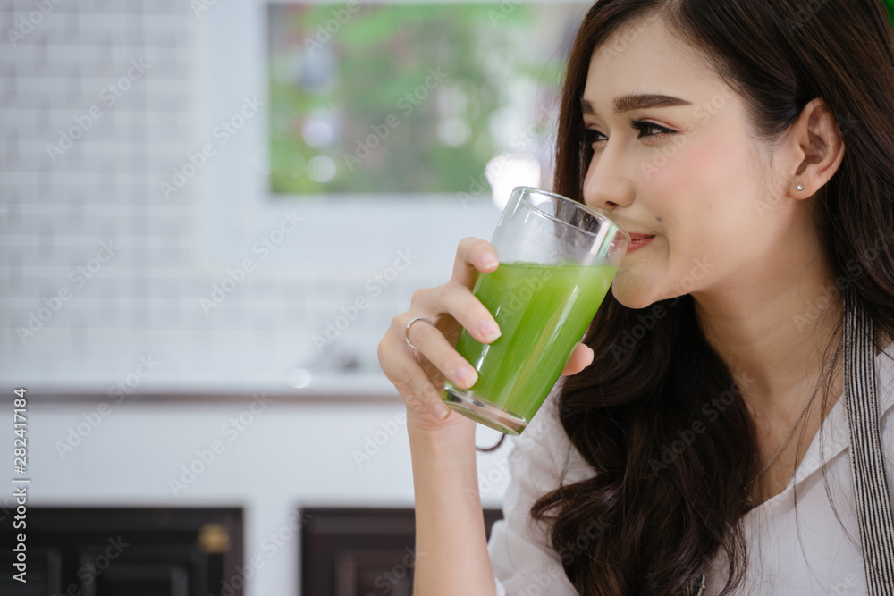 young girl drinking green cocktail with a straw.Woman drinking a homemade green detox juice. texting on her phone while sitting in her kitchen table young girl drinking green cocktail with a straw.Woman drinking a homemade green detox juice. texting on her phone while sitting in her kitchen table