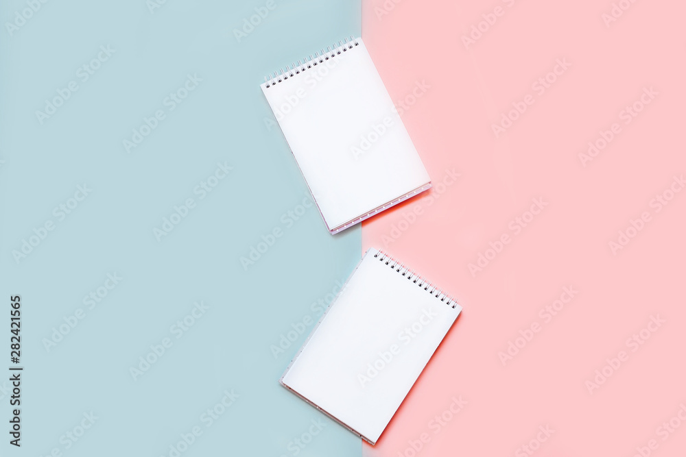 Fototapeta premium Two notebooks with blank white sheets on a pink and blue background