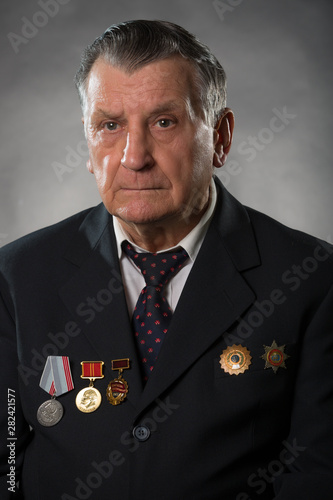 Portrait of an elderly gray haired man. On his chest medals of the Soviet period. A war veteran and hero of socialist labor. Studio photography.
