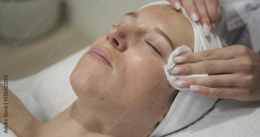 Beautician cleaning the face with tissue at beauty salon Beautician cleaning the face with tissue at beauty salon