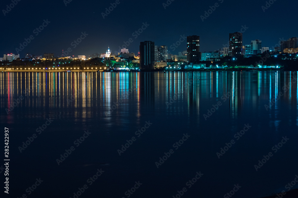 Night View of the city of Khabarovsk from the Amur river. Blue night sky. The night city is brightly lit with lanterns. The level of the Amur river at around 159 centimeters.