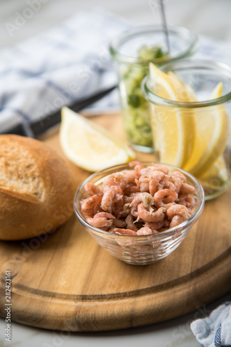 Norddeutsche Friesische Nordseekrabben in Glas Schale mit Brötchen, Gurkensalat und Zitronen auf Holz Brett photo