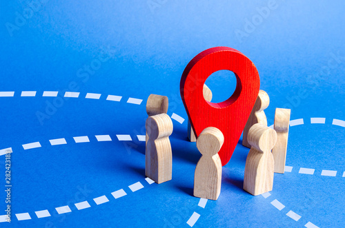 People gathered around the red navigation pointer pin. Meeting place concept. A long awaited meeting, a company of friends, acquaintance via the Internet. Event or holiday. Organization of joint trip photo