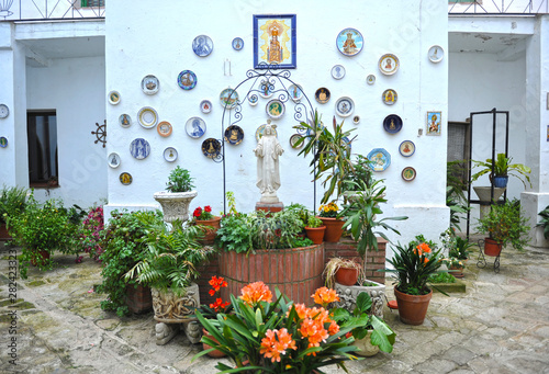 Patio with water well decorated with flower pots and religious images of Jesus Christ and the Virgin. Pilgrim hostel House of Mercy in Alcuescar, Extremadura, Spain photo
