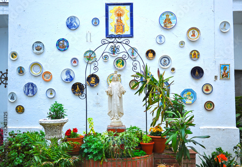 Patio with water well decorated with flower pots and religious images of Jesus Christ and the Virgin. Pilgrim hostel House of Mercy in Alcuescar, Extremadura, Spain photo