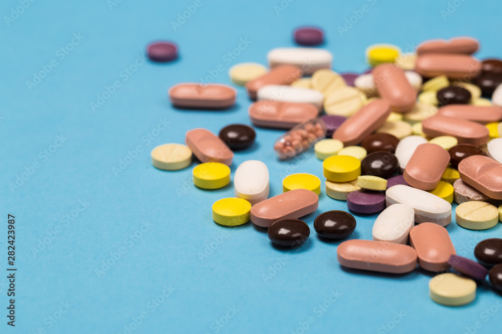 many scattered Colorful medical pills on pastel blue background many scattered Colorful medical pills on pastel blue background