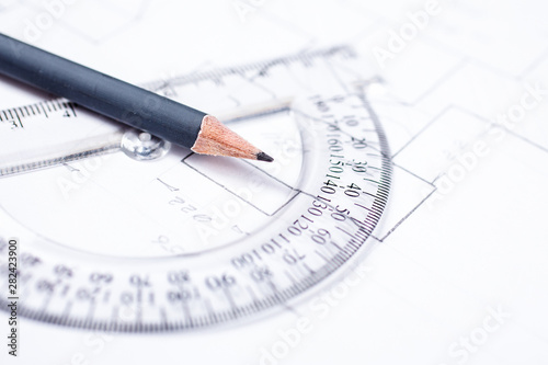 Pencil on a transparent protractor against the background of drawing details