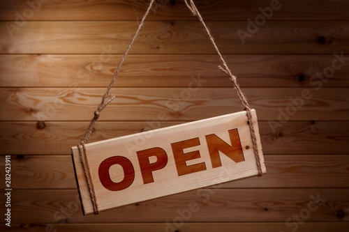 Wooden signboard with the words OPEN on a rough rope on a beautiful wooden background