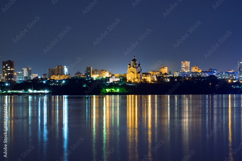 Night View of the city of Khabarovsk from the Amur river. Blue night sky. The night city is brightly lit with lanterns. The level of the Amur river at around 159 centimeters.