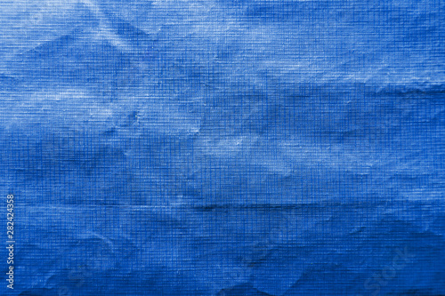 Dirty crumpled blue synthetic fabric texture with a well-traced light and shadow pattern