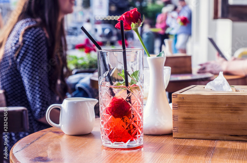 Photo mojito from strawberries. Red rose in a white vase in the background.