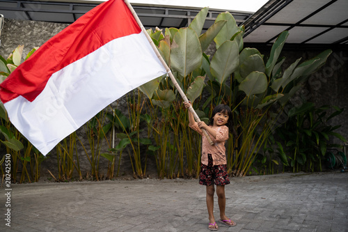 asian little girl flapping Indonesian flag with spirit at yard home photo